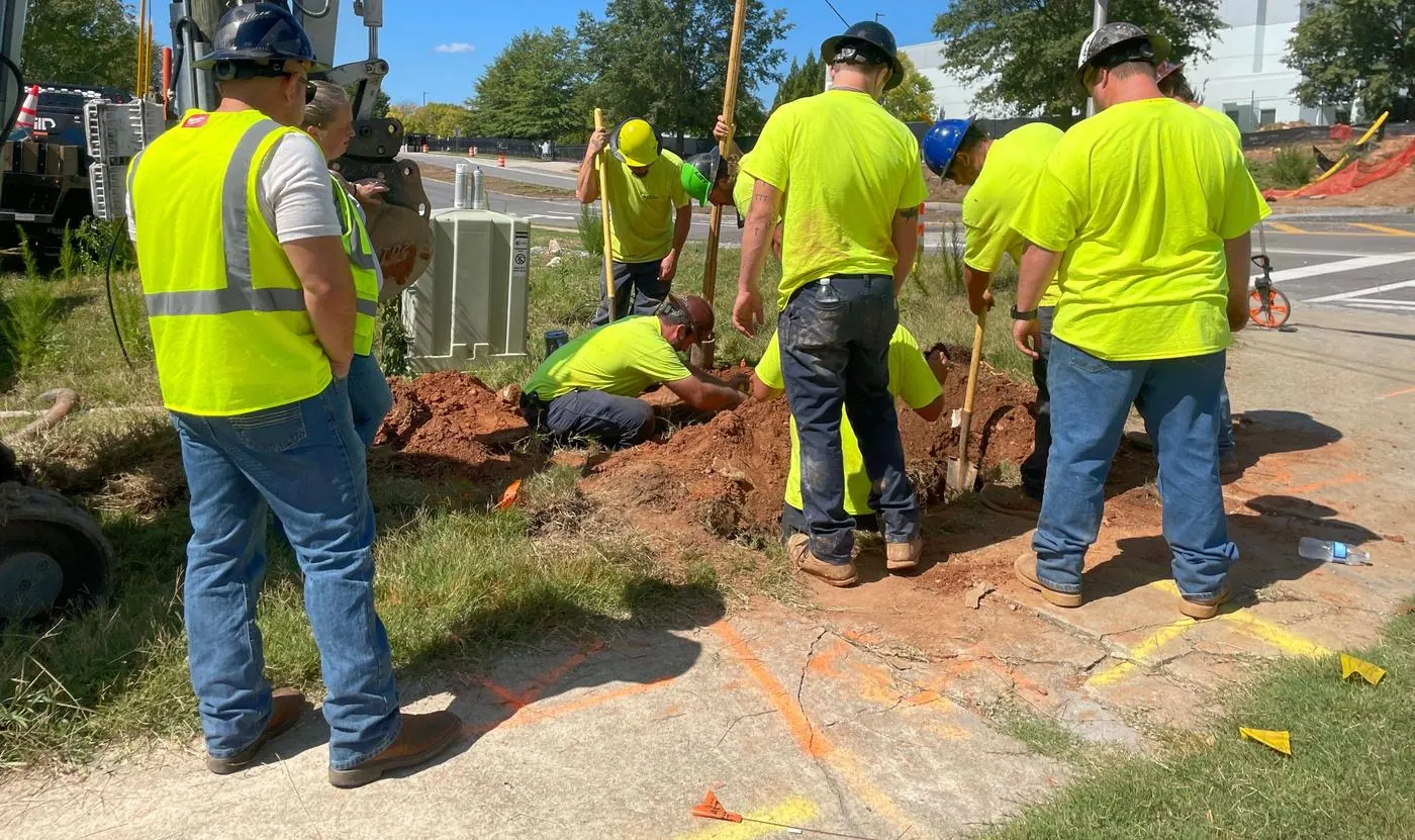 Crew excavating beside a utility cabinet